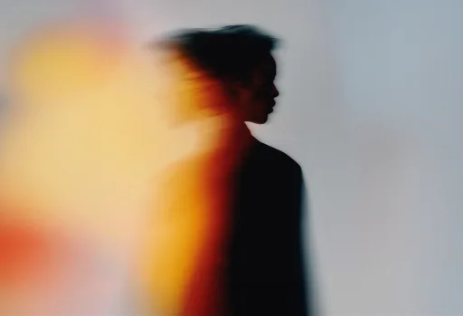 A figure moving through warm light